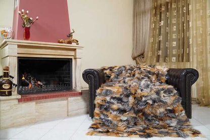 Fur Throw Blanket Natural Gross Fox – Luxury - Tatifurs draped over a leather couch by a cozy fireplace.