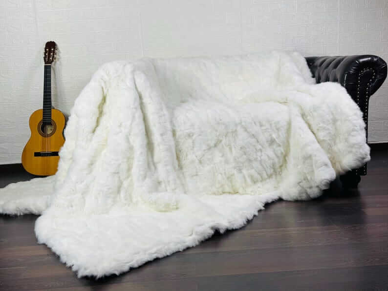 White Rabbit Fur Throw Blanket - Tatifurs draped over a couch with a guitar in the background.