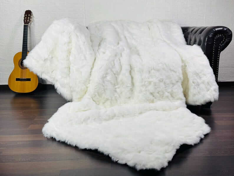 White Rabbit Fur Throw Blanket - Tatifurs draped on a couch beside a guitar, showcasing a soft, luxurious texture.