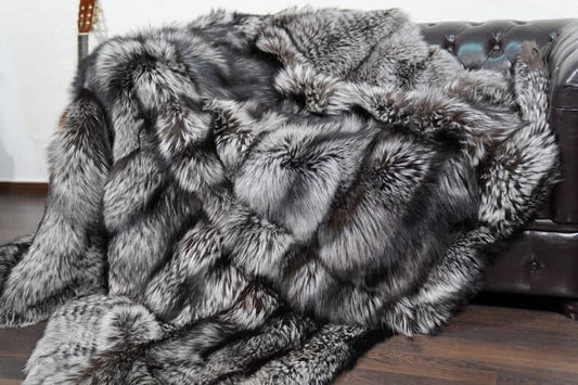 Natural silver fox fur blanket draped over bed showing luminous silver tones and depth
