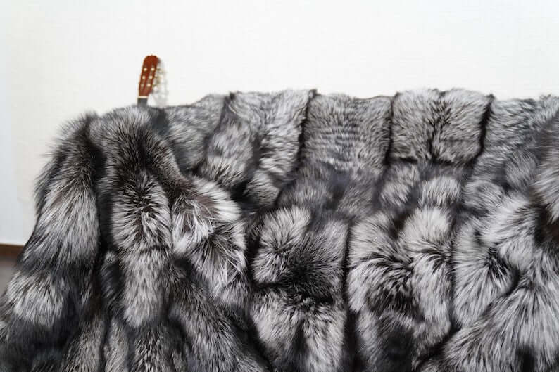 Fox Fur Blanket Throw Silver Natural - Tatifurs displayed on a surface, showcasing its luxurious silver fox fur texture.