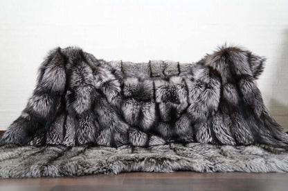 Fox Fur Blanket Throw Silver Natural - Tatifurs displayed elegantly on a wooden surface, showcasing its luxurious silver fox fur texture.
