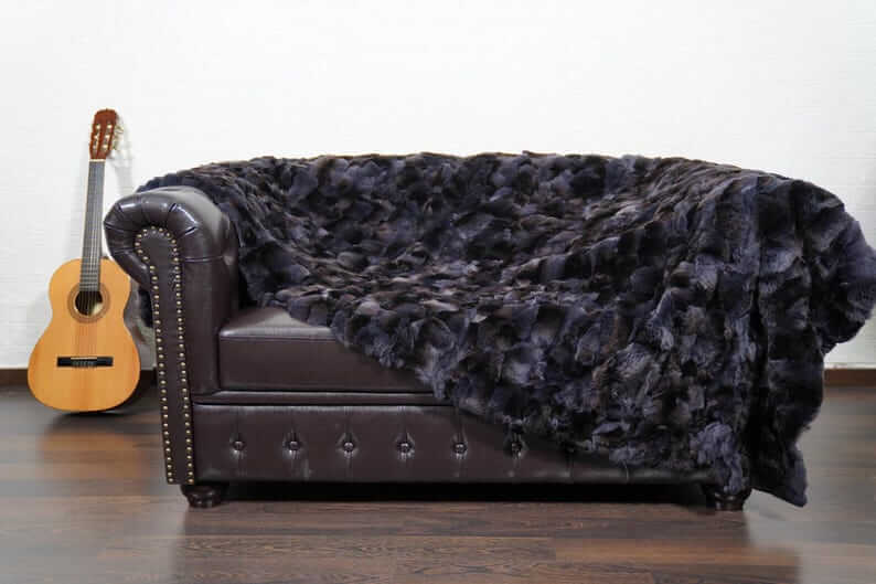 Rabbit Blanket Throw Rex Gray Orchid - Tatifurs draped over a leather sofa with a guitar nearby.