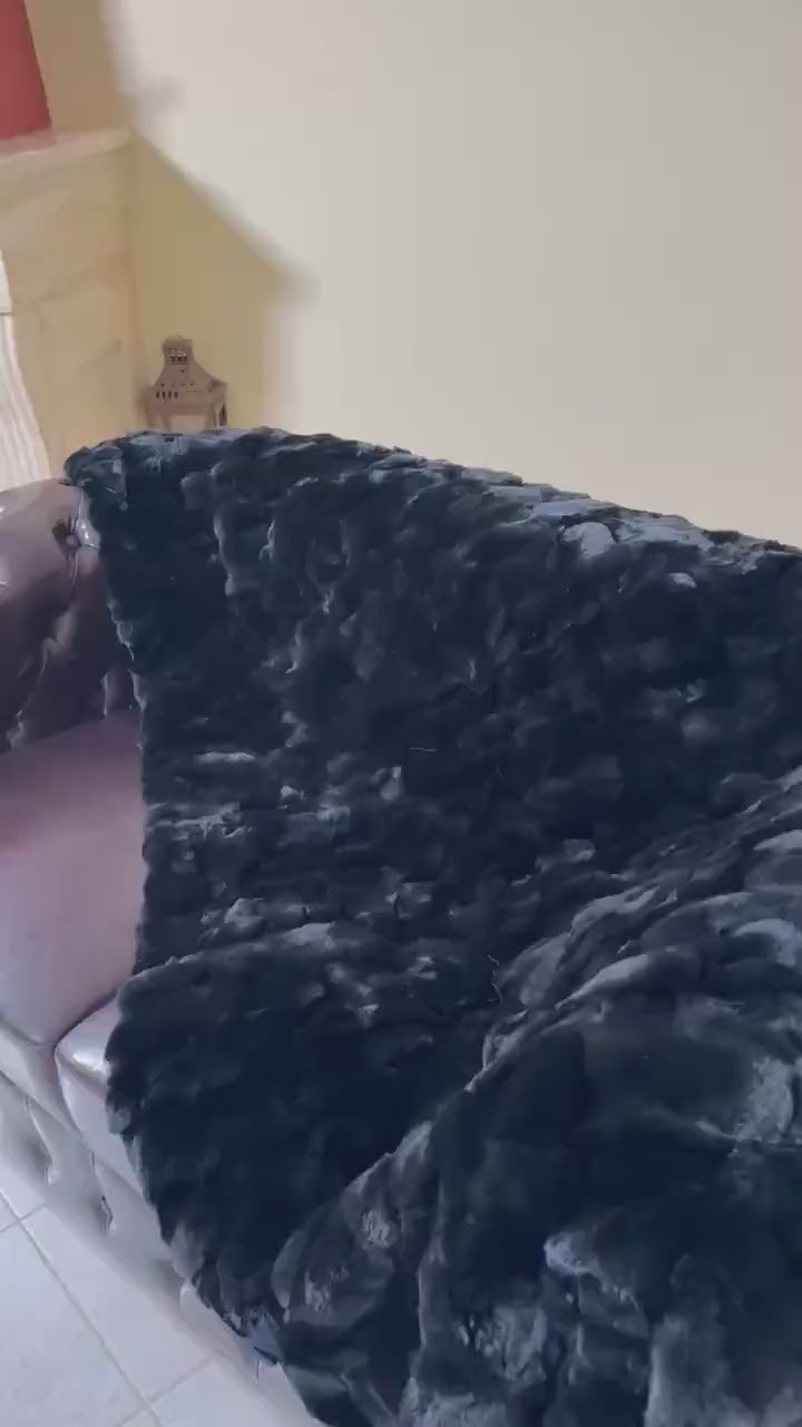 Double Sided Fur Rex Rabbit Blanket Throw Black draped over a couch, showcasing its luxurious texture.