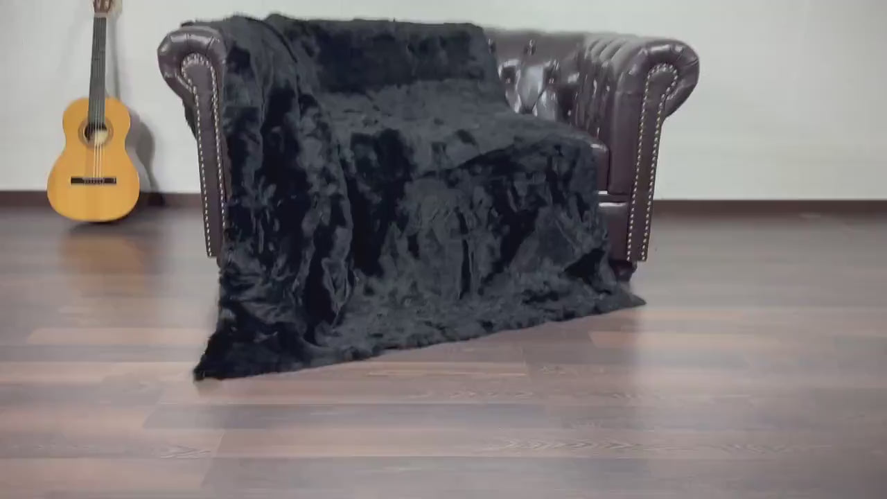 Rabbit Fur Blanket Throw Black - Tatifurs displayed on a brown leather sofa with a guitar in the background.