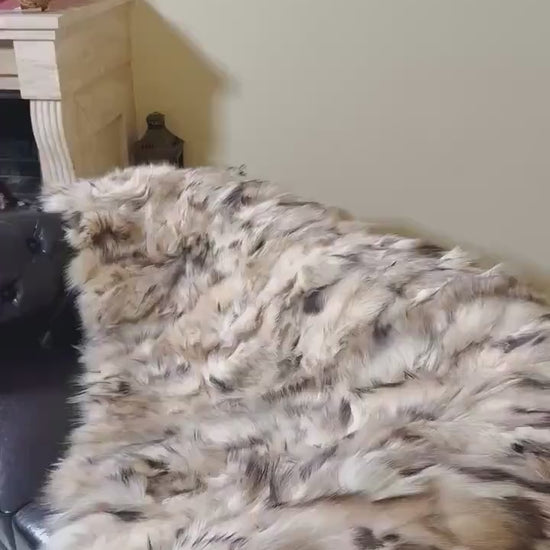 Fox Fur Blanket Throw Double Sided Iceberg Beige draped on a couch, showcasing its warm beige and soft fur texture.