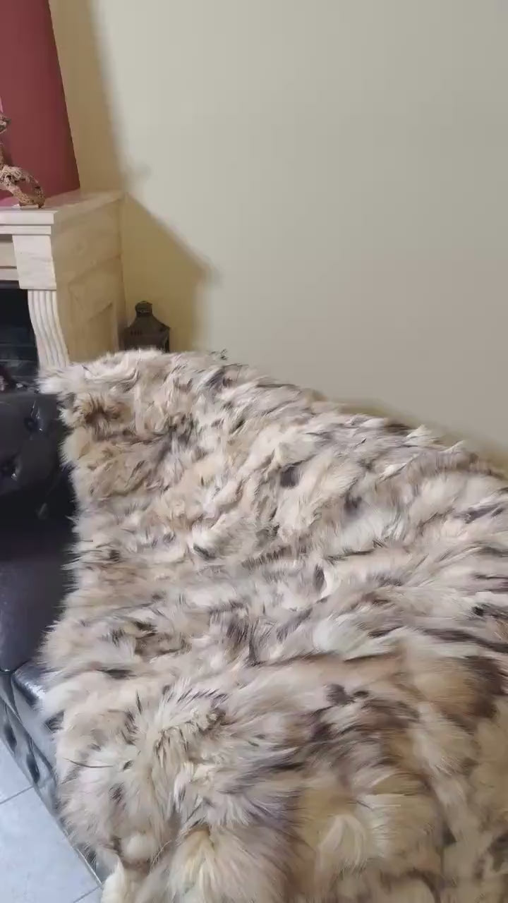 Fox Fur Blanket Throw Double Sided Iceberg Beige draped on a couch, showcasing its warm beige and soft fur texture.