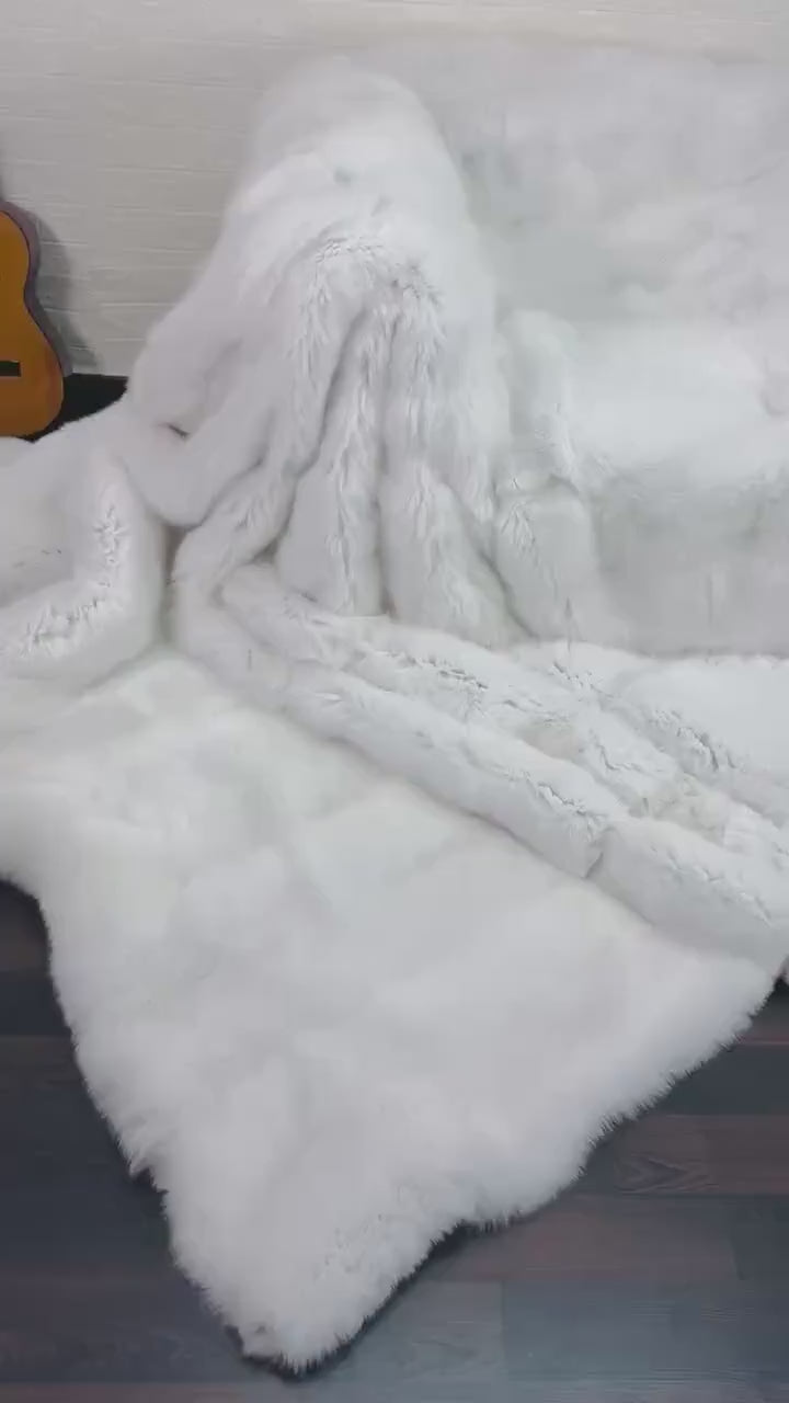 White Fox Fur Throw Blanket - Tatifurs draped elegantly over a couch, showcasing its luxurious pure white fur.
