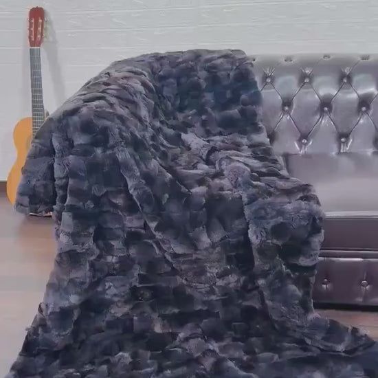 Rabbit Blanket Throw Rex Gray Orchid - Tatifurs draped over a brown leather couch, adding a touch of elegance to the room.