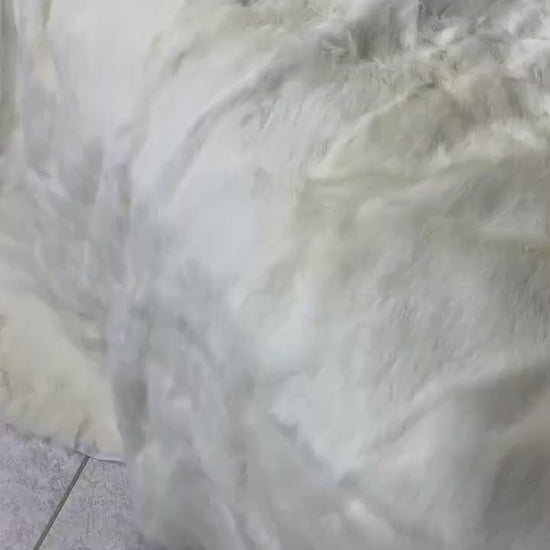 White Rabbit Fur Throw Blanket - Tatifurs displayed on a tiled floor, showcasing its soft and luxurious texture.