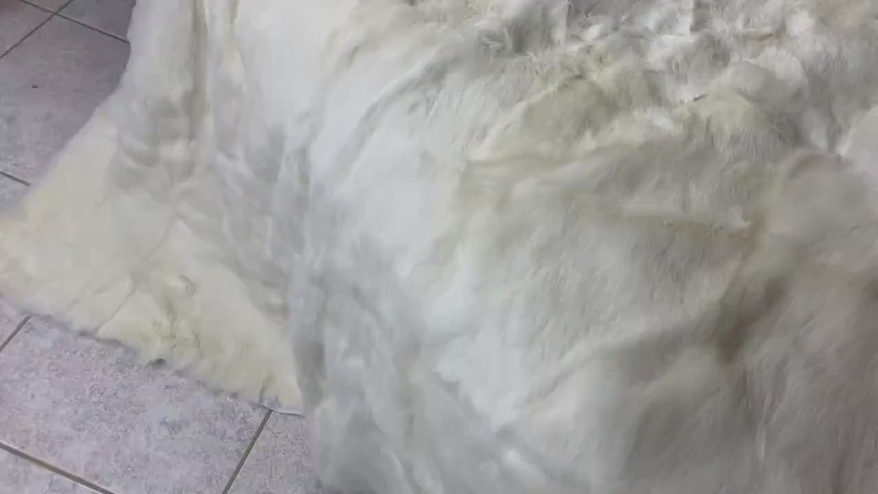 White Rabbit Fur Throw Blanket - Tatifurs displayed on a tiled floor, showcasing its soft and luxurious texture.