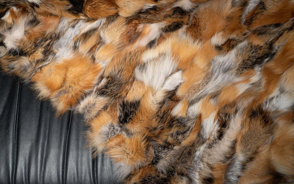 Fox Fur Blanket Throw Red Canadian Dark - Tatifurs on a soft black leather couch.