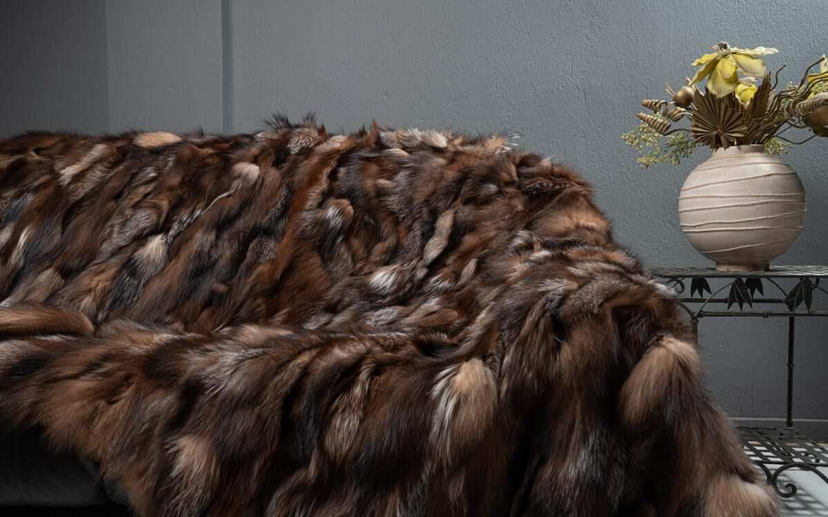 Fox Fur Blanket Throw Crystal Dark - Tatifurs draped on a sofa, showcasing its rich textures and natural beauty.