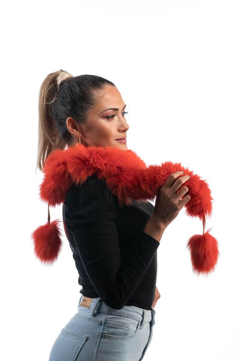 Orange Fox Fur Scarf with Pom Poms - Tatifurs modeled by a woman, showcasing its vibrant color and fluffy texture.
