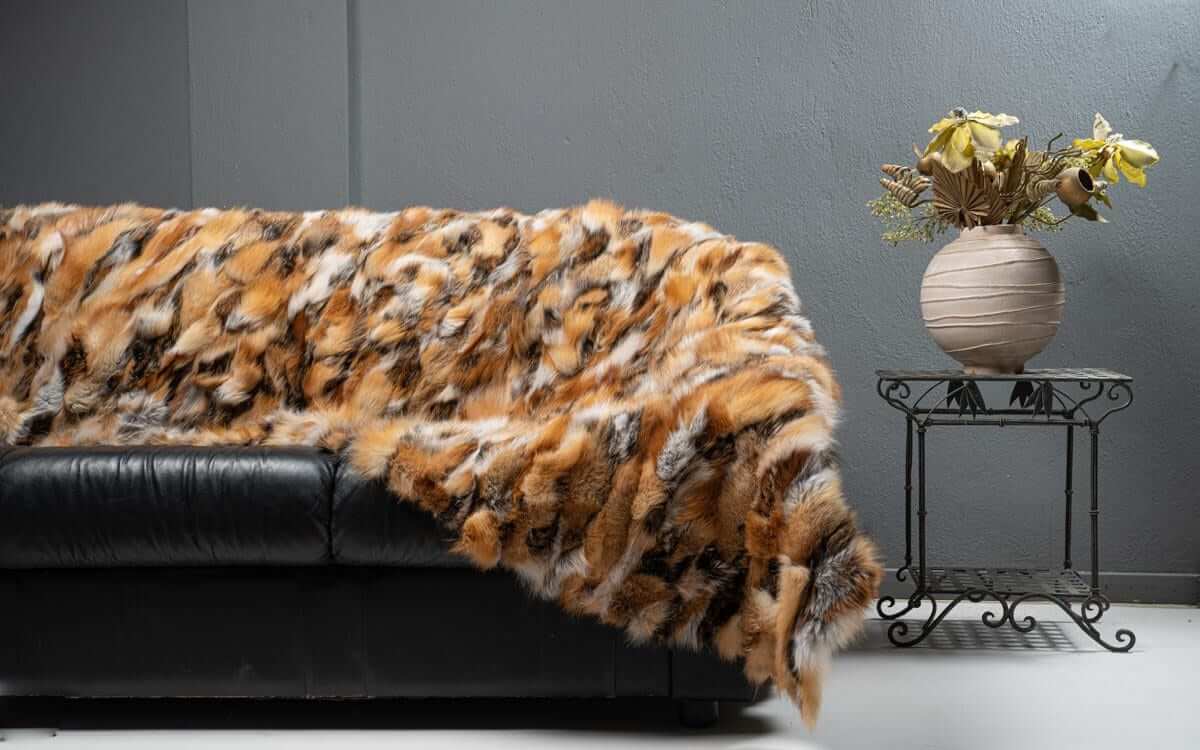 Fox Fur Blanket Throw Red Canadian Dark - Tatifurs draped over a black sofa with a decorative vase.
