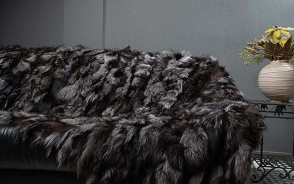 Fox Fur Blanket Throw Silver Dark - Tatifurs draped elegantly over a couch, showcasing its rich charcoal and silver tones.