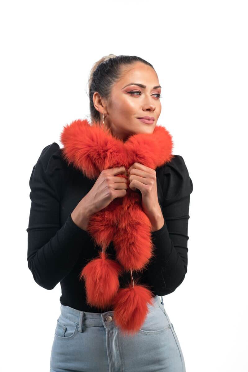 Orange Fox Fur Scarf with Pom Poms - Tatifurs worn by a woman, showcasing the vibrant color and playful design.