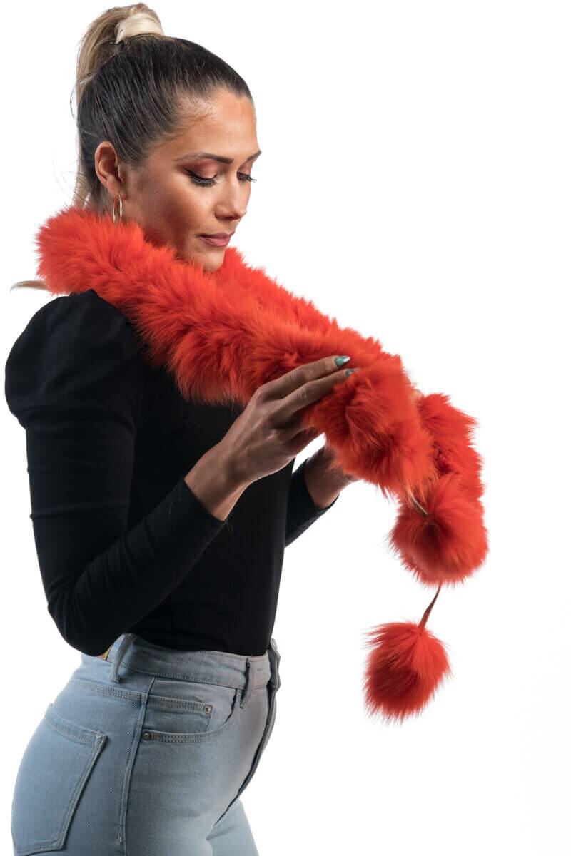 Orange Fox Fur Scarf with Pom Poms - Tatifurs being held by a model, showcasing its vibrant color and playful pom poms.