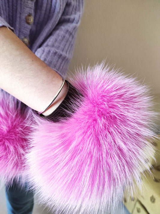 Woman wearing fuchsia pink fox fur cuffs on wrists showing vivid electric pink color
