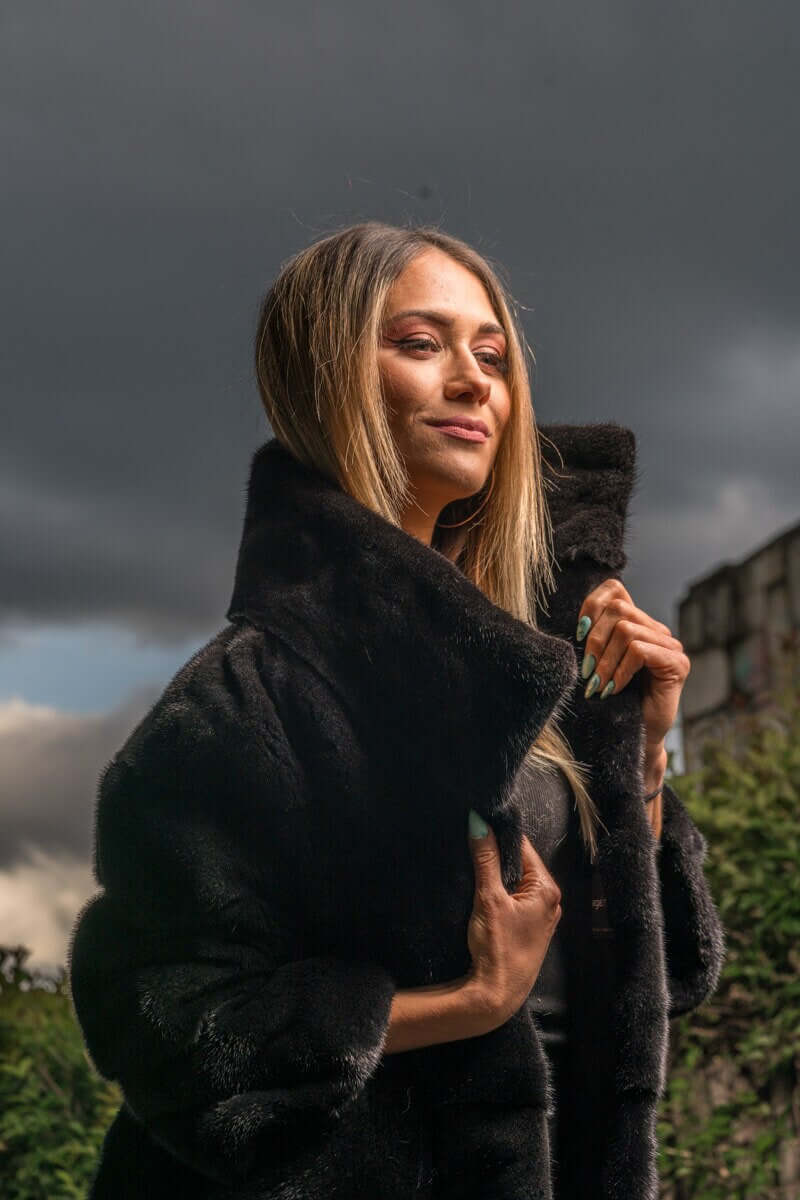 Mink Fur Jacket Black with collar - Tatifurs worn by a model against a cloudy background.