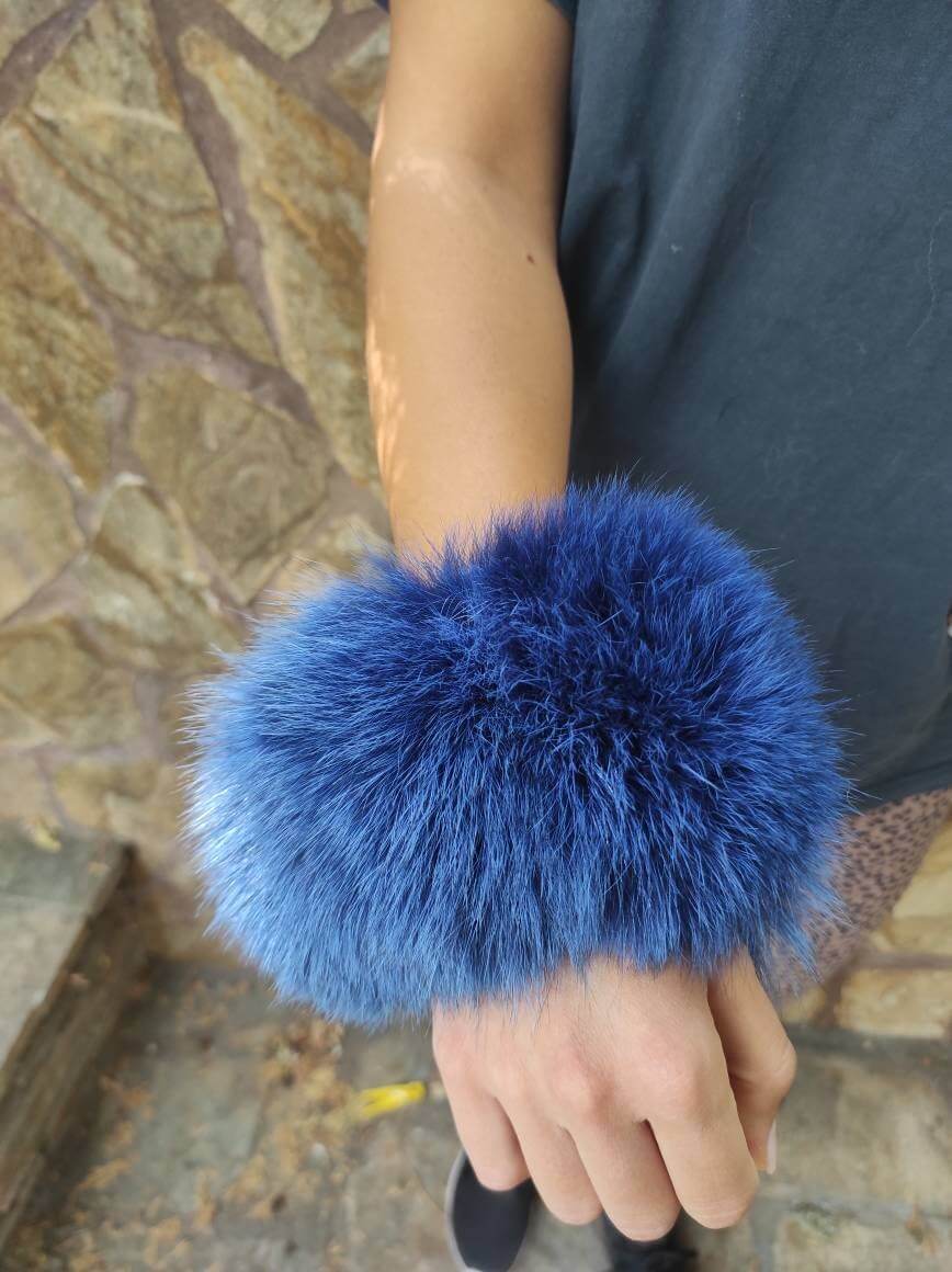 Blue Fox Fur Cuffs - Tatifurs worn on the wrist showcasing vibrant blue color and luxurious texture.